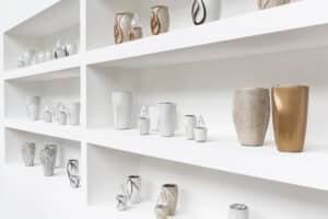 White shelving unit with a multitude of artistic urns of different shapes and colors